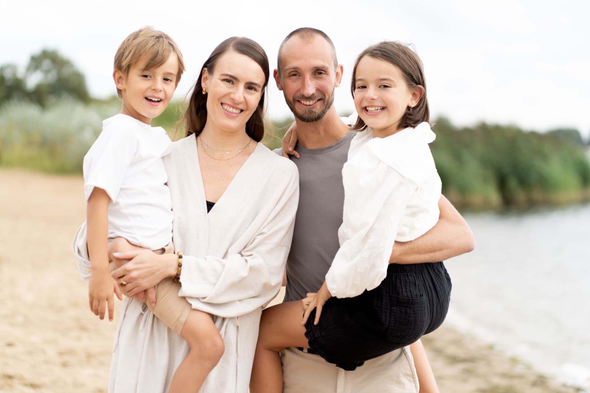 Parents holding their two children on a sandy shore