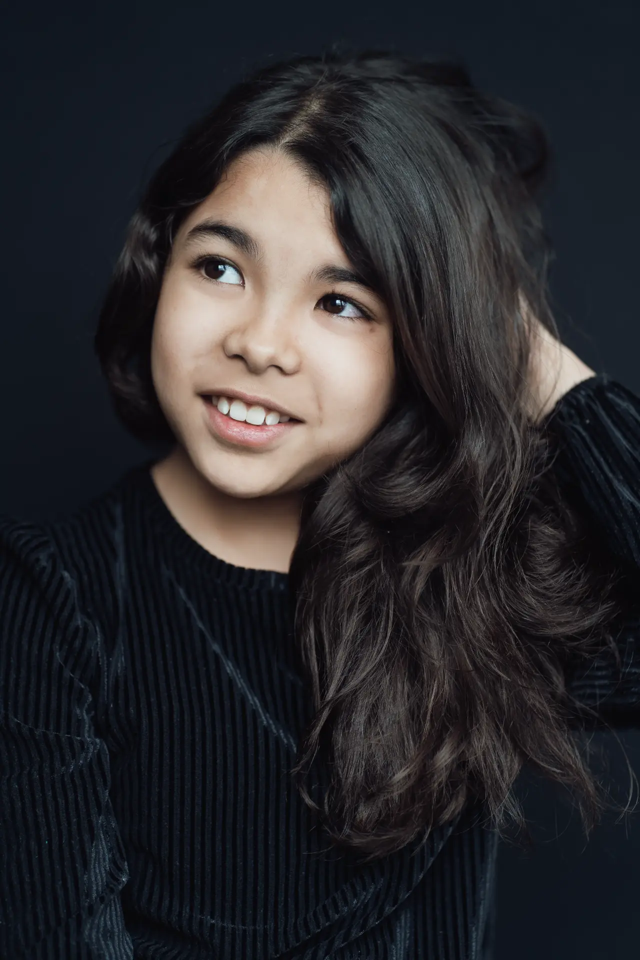 Girl with long dark hair in black against a charcoal backdrop