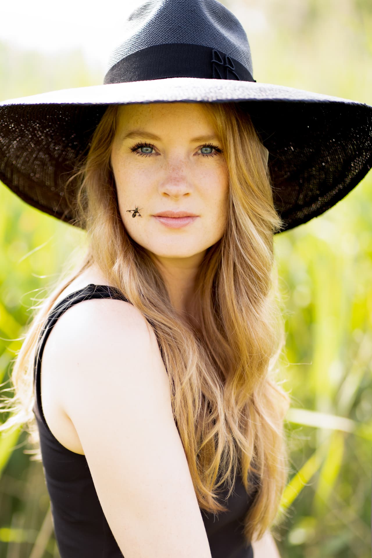 Woman in a wide black sun hat in a sunlit field
