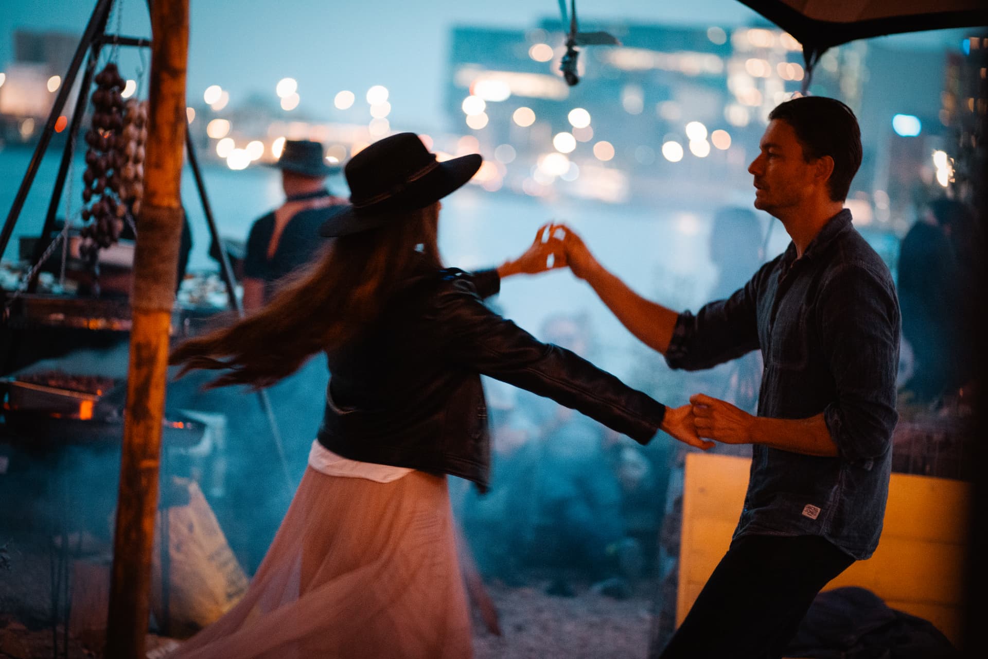 A couple dancing together beneath evening lights
