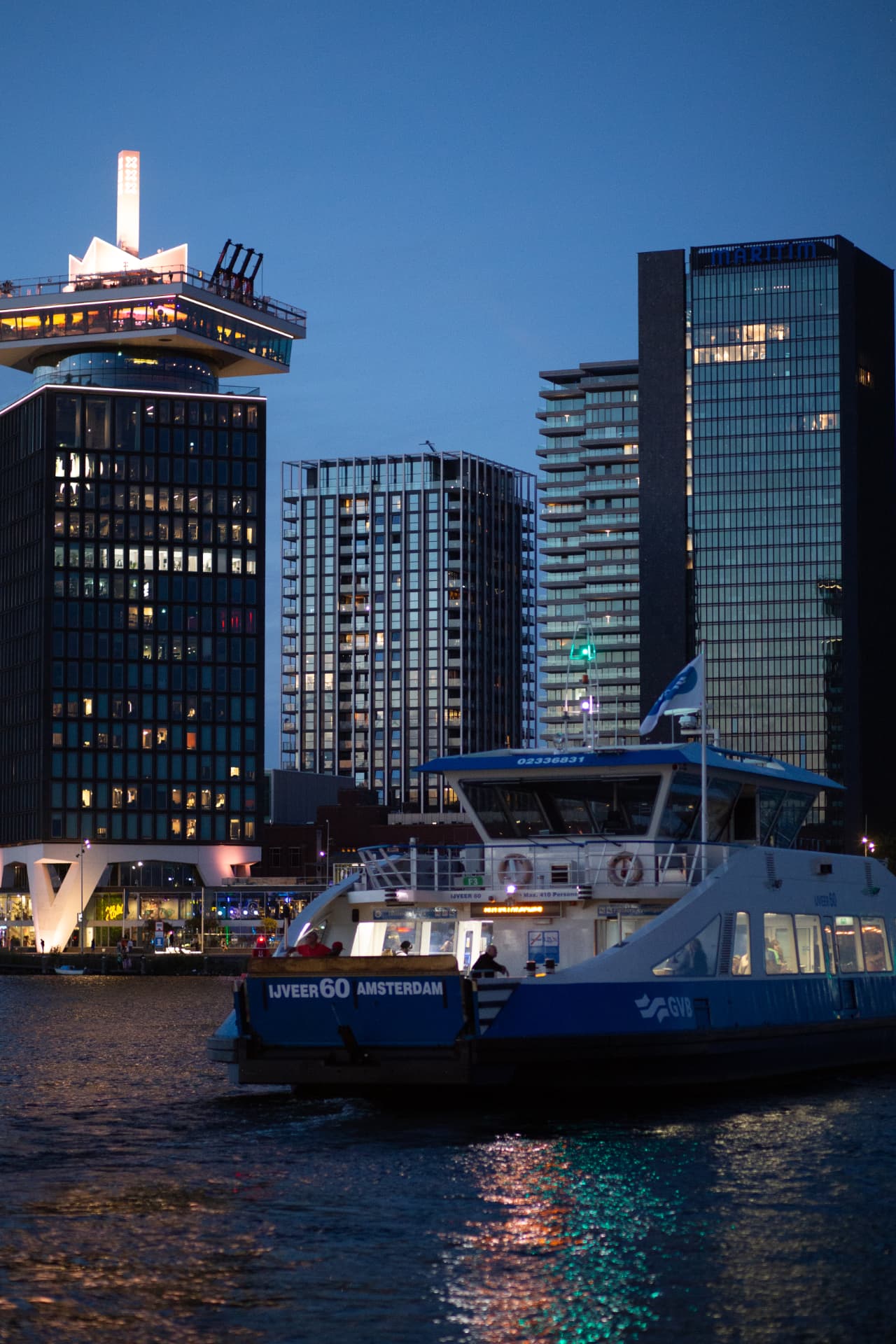 Amsterdam ferry passing the waterfront skyline at blue hour