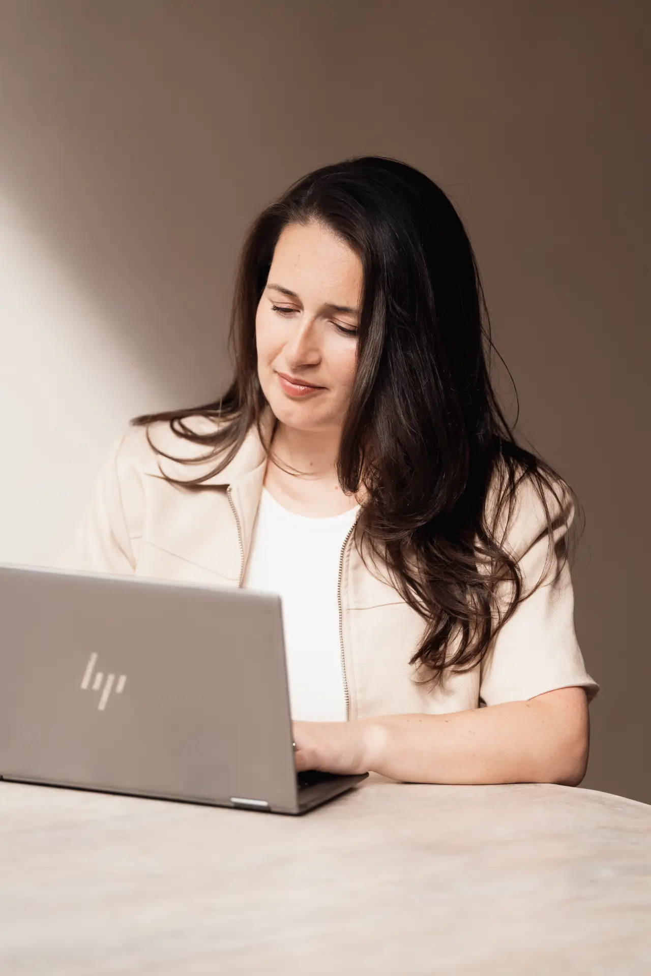 Suzana working on her laptop in warm window light