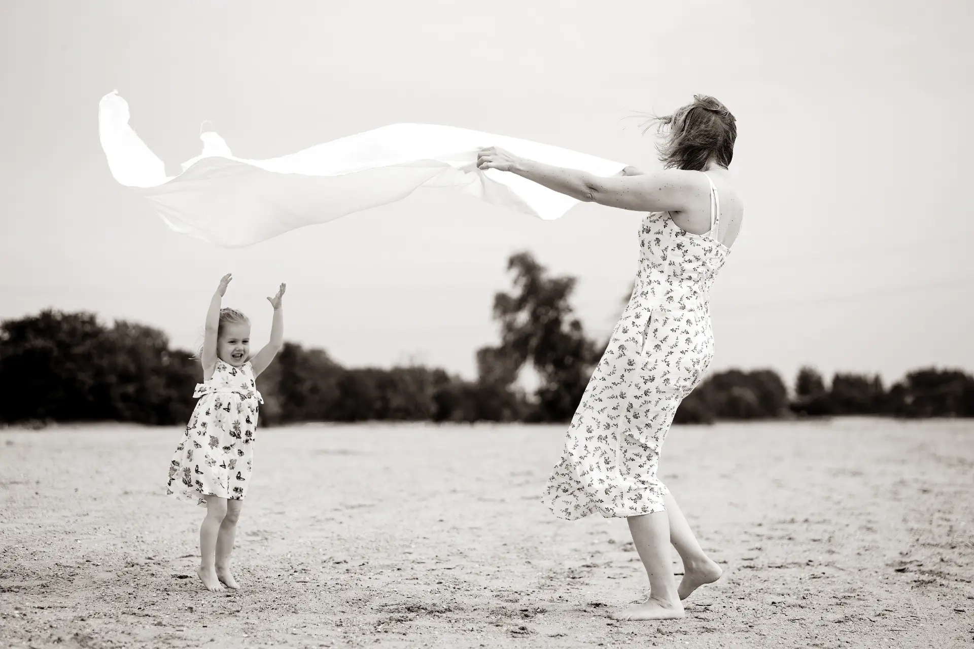 Mother waving a white sheet in the wind while her daughter cheers