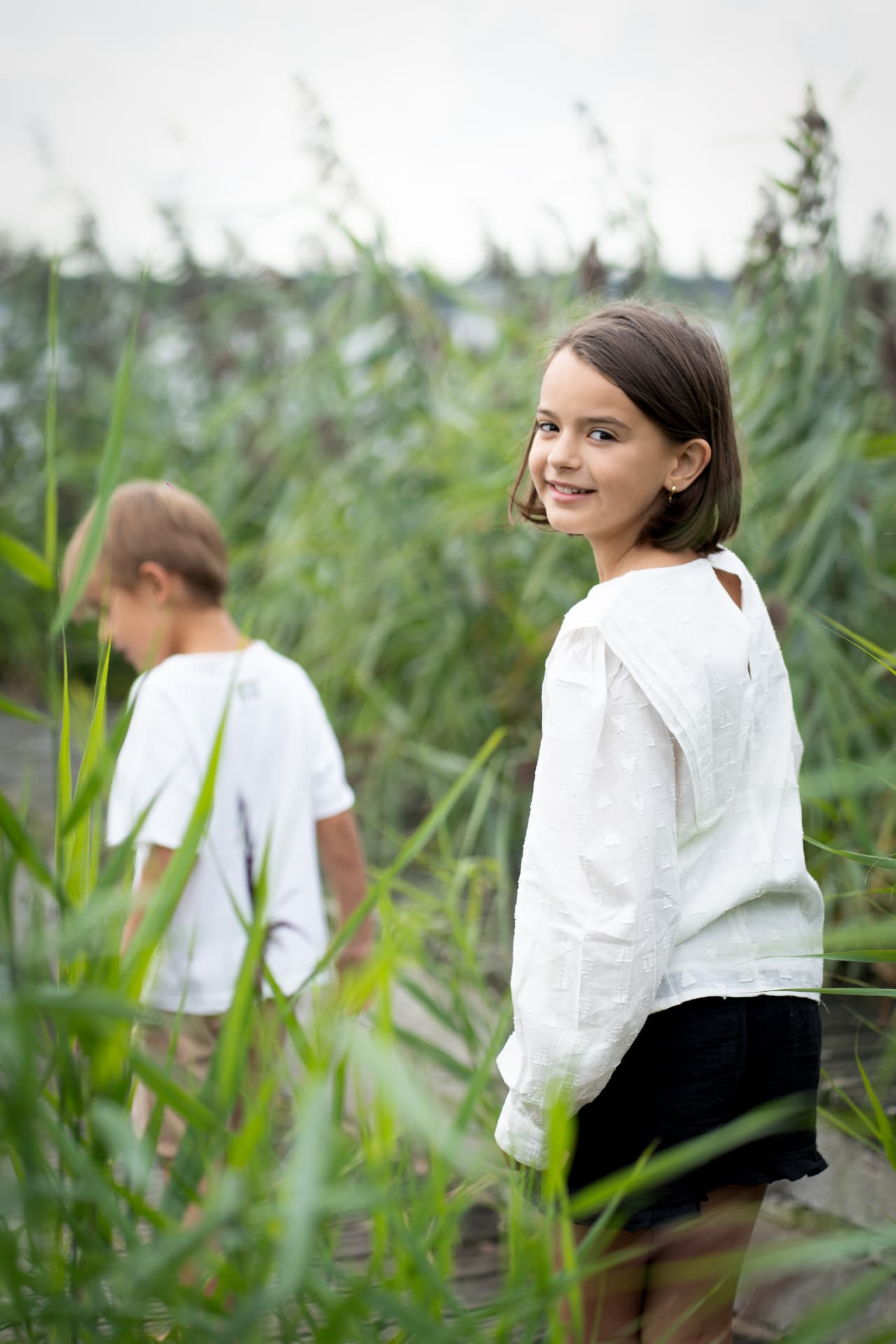 Girl looking back over her shoulder through tall grass