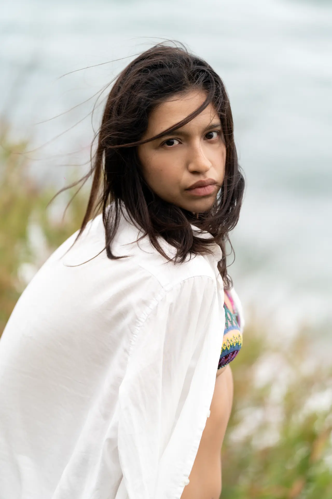 Woman in a white shirt with wind in her hair by the sea