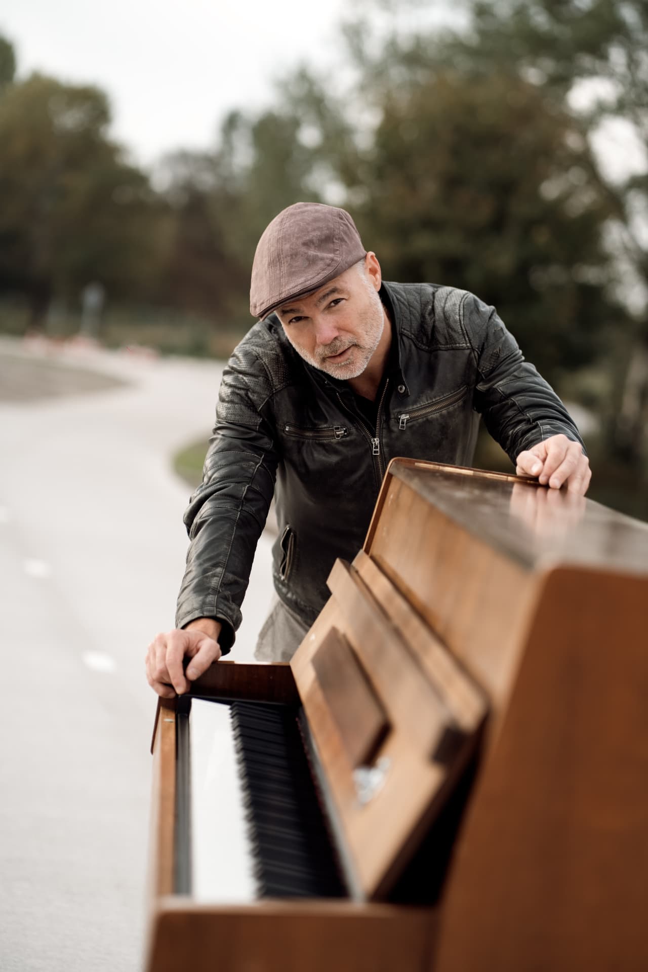 Peter in a leather jacket leaning over his piano