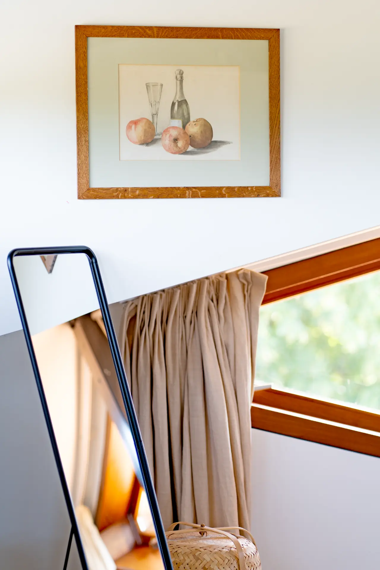 A mirror and framed still life in the corner of the bedroom