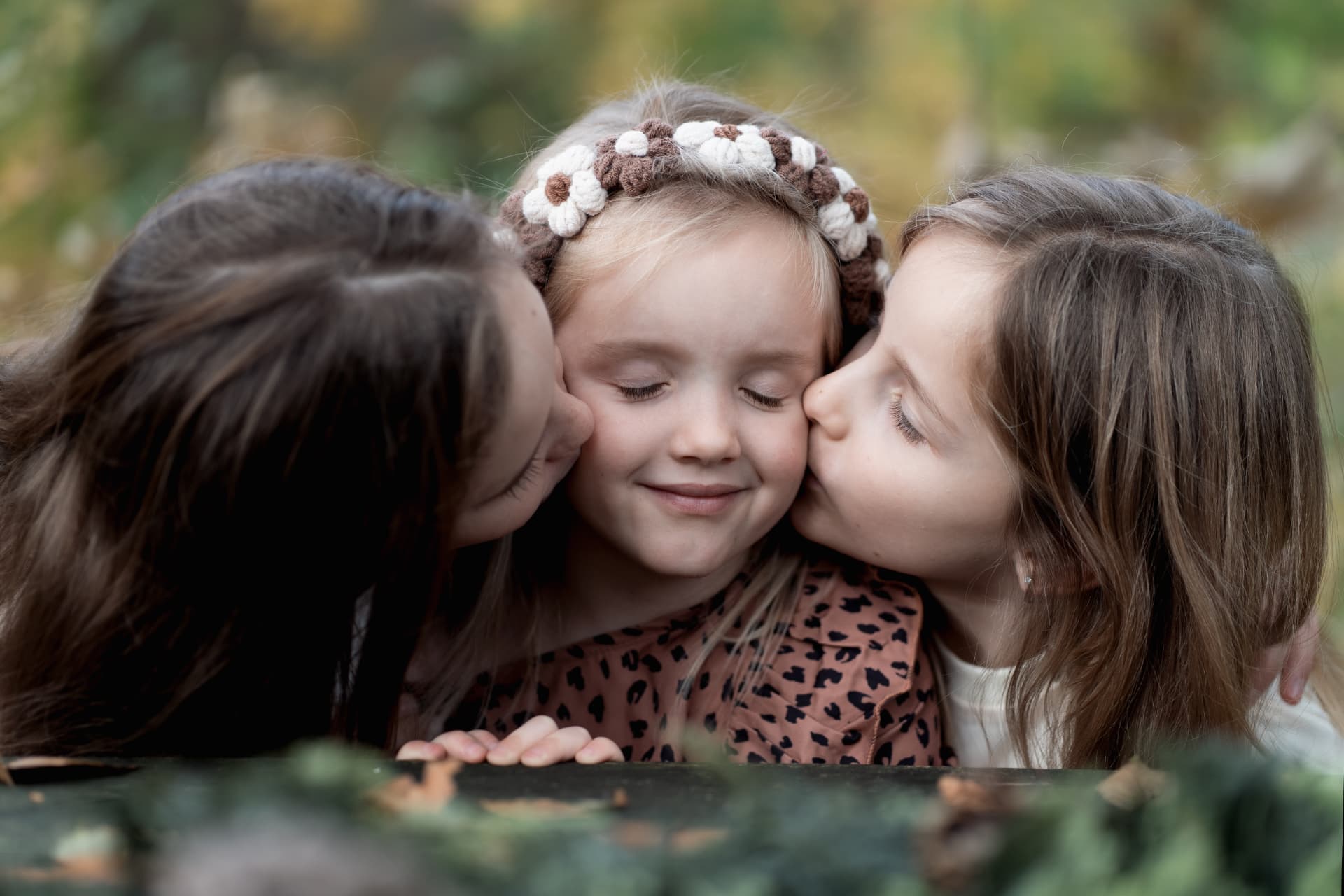Three sisters sharing a kiss at the autumn table