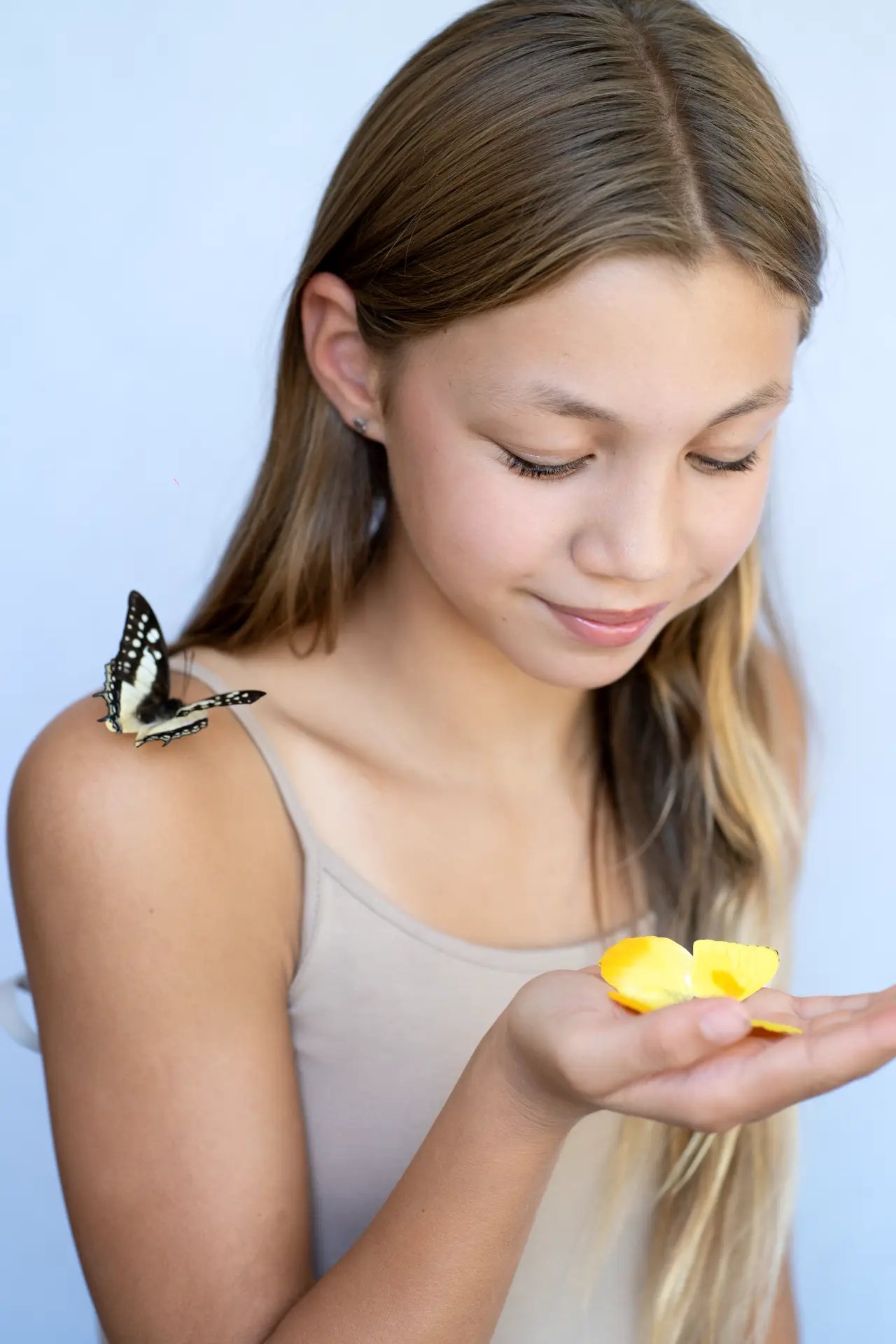 Girl looking down at a butterfly resting in her cupped hands