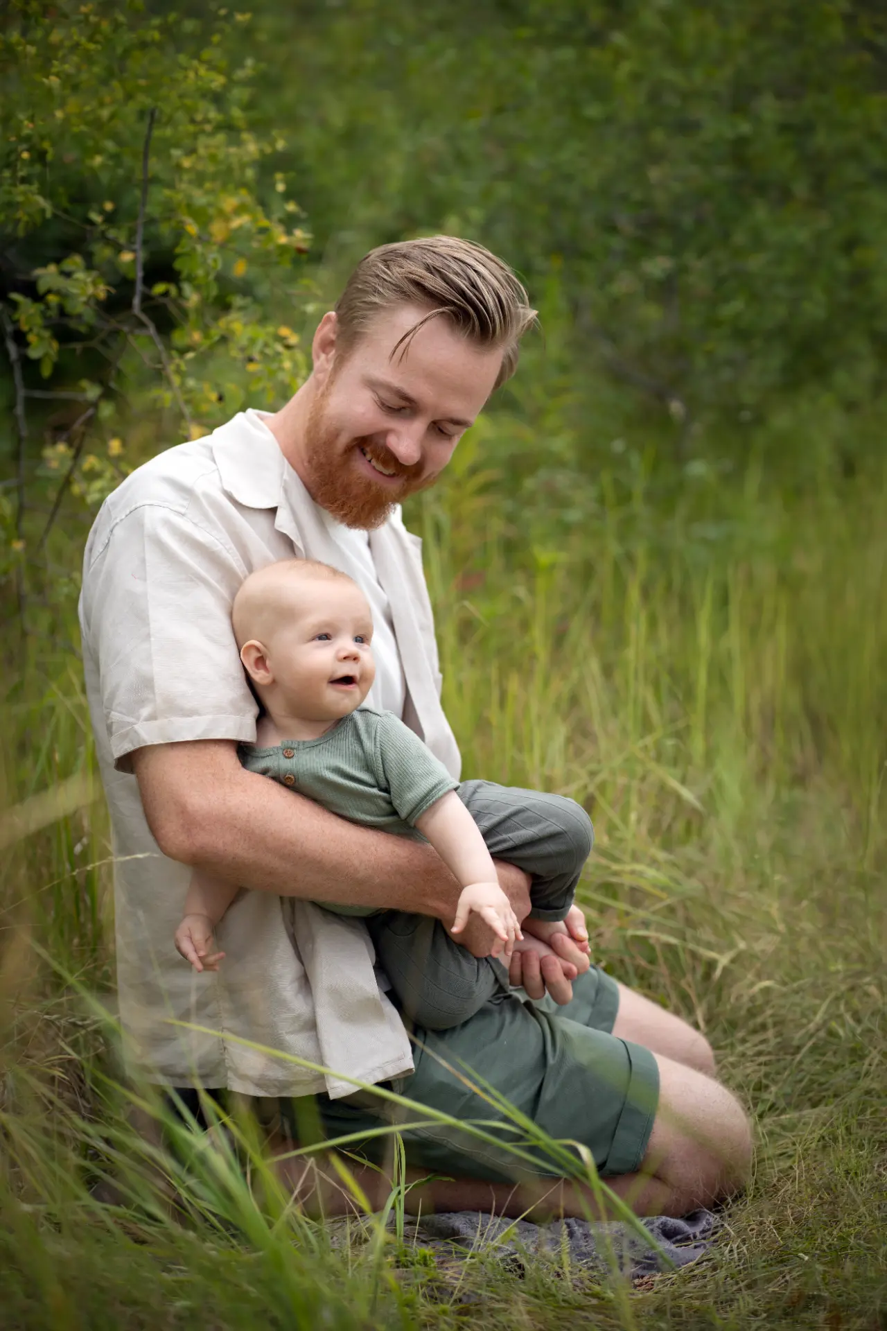 Father laughing with his baby in a green meadow