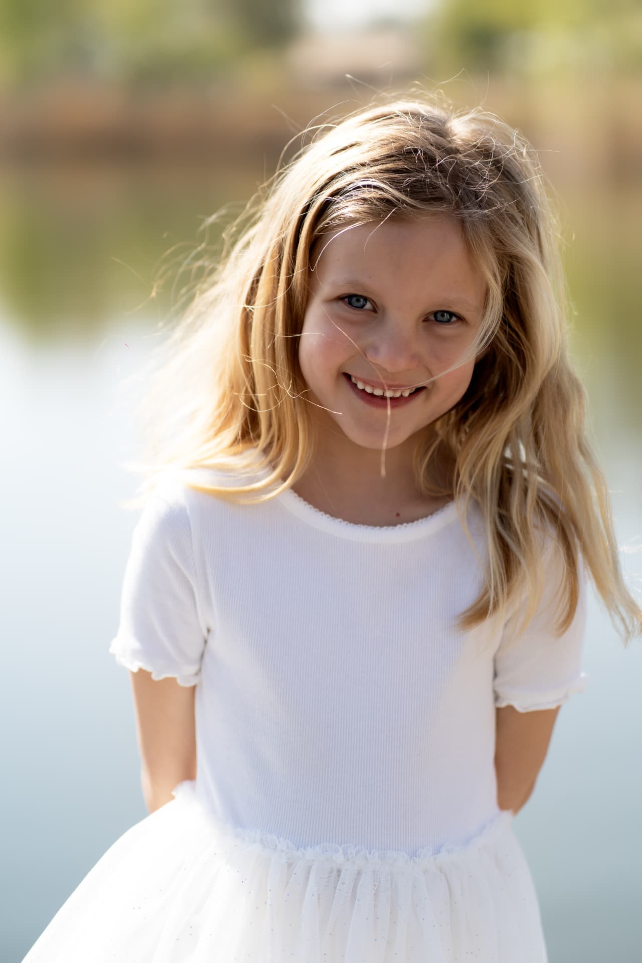 Portrait of a girl in a white dress smiling by the water