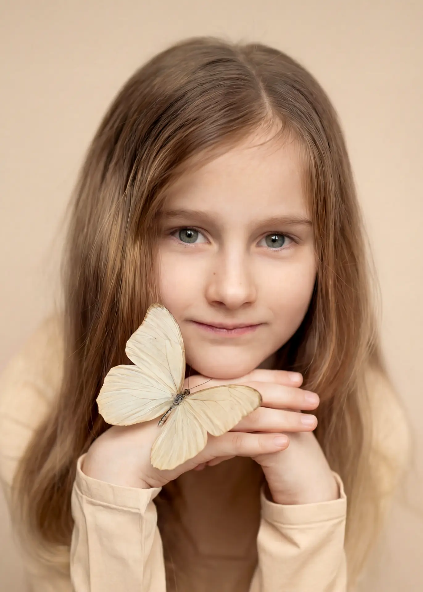 Girl in warm neutral tones holding a pale butterfly