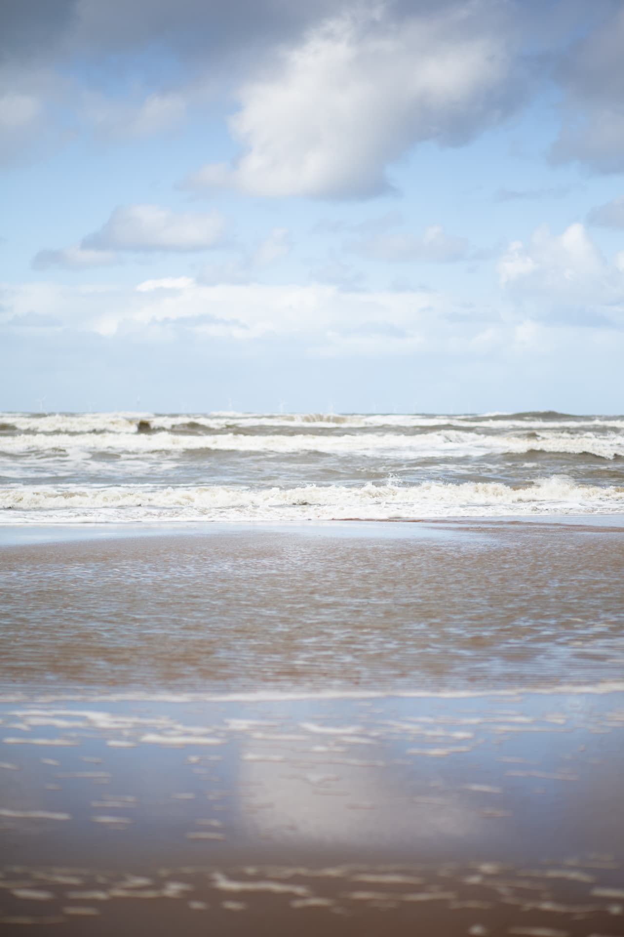 Sea and sky reflected across the wet shoreline