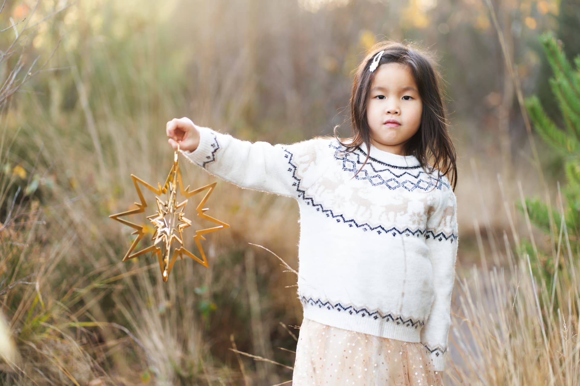 Girl holding a golden star in winter sunlight