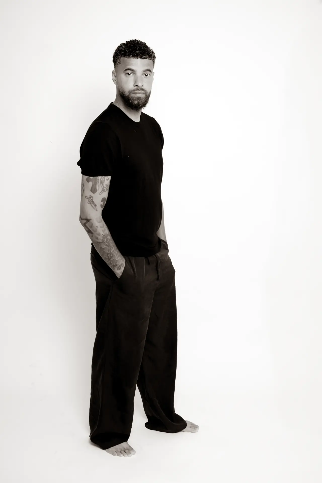 Full-length portrait of a man in black on a white backdrop