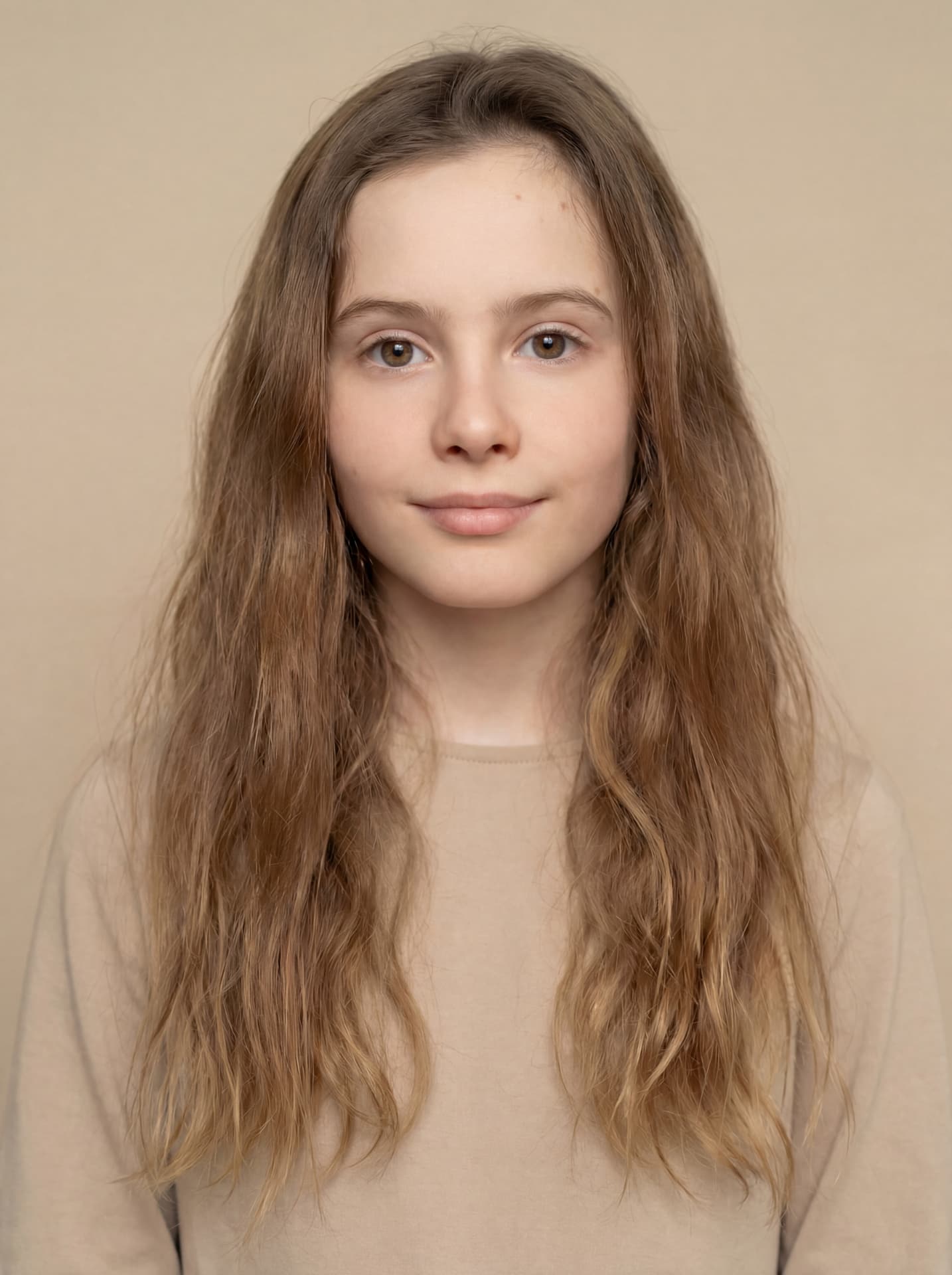 Girl with long brown hair in a beige top against a warm neutral backdrop