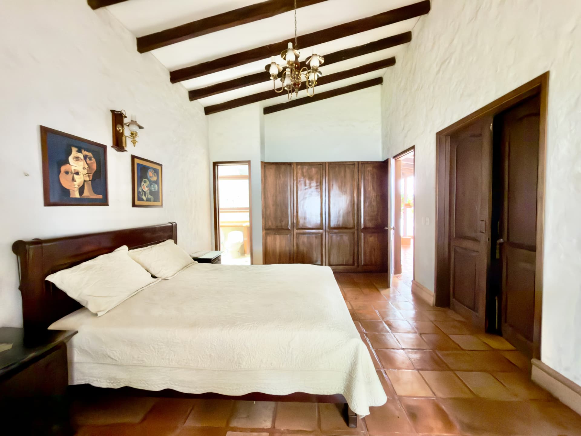 Main bedroom with a wooden bed, beamed ceiling and terracotta floor