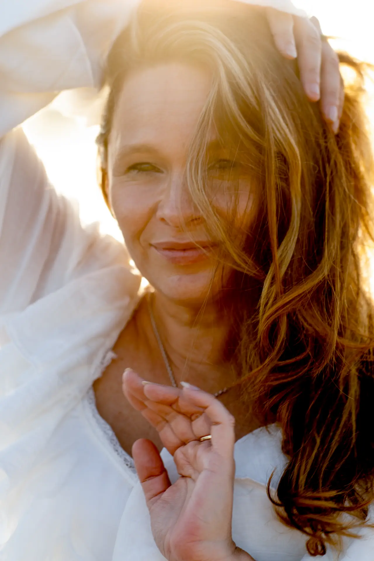 Woman running her hands through her hair in backlit golden light