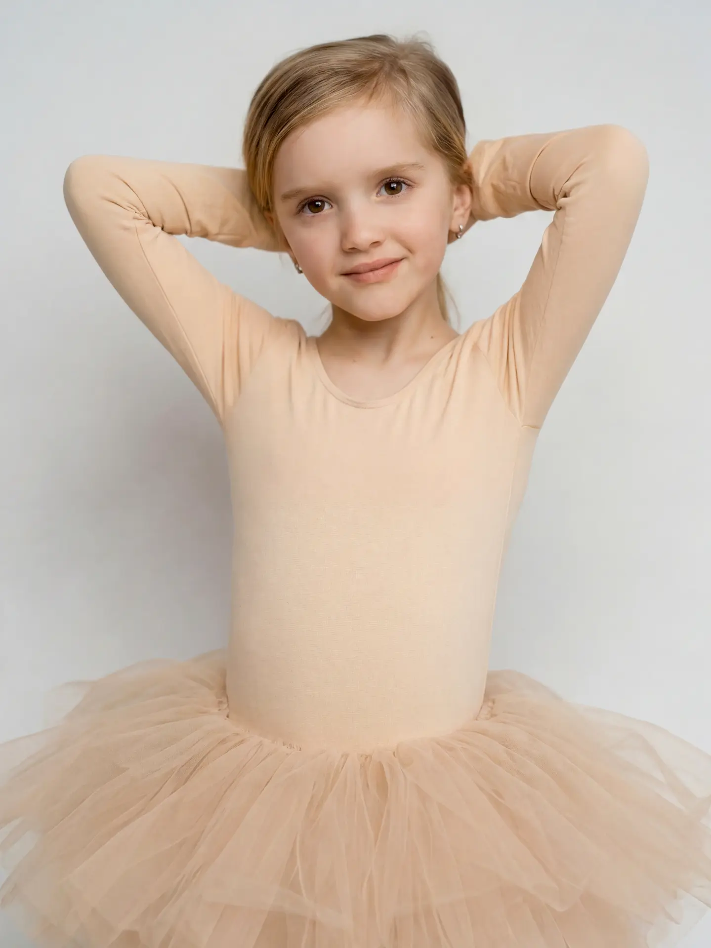 Young dancer in a soft beige dress against a pale backdrop