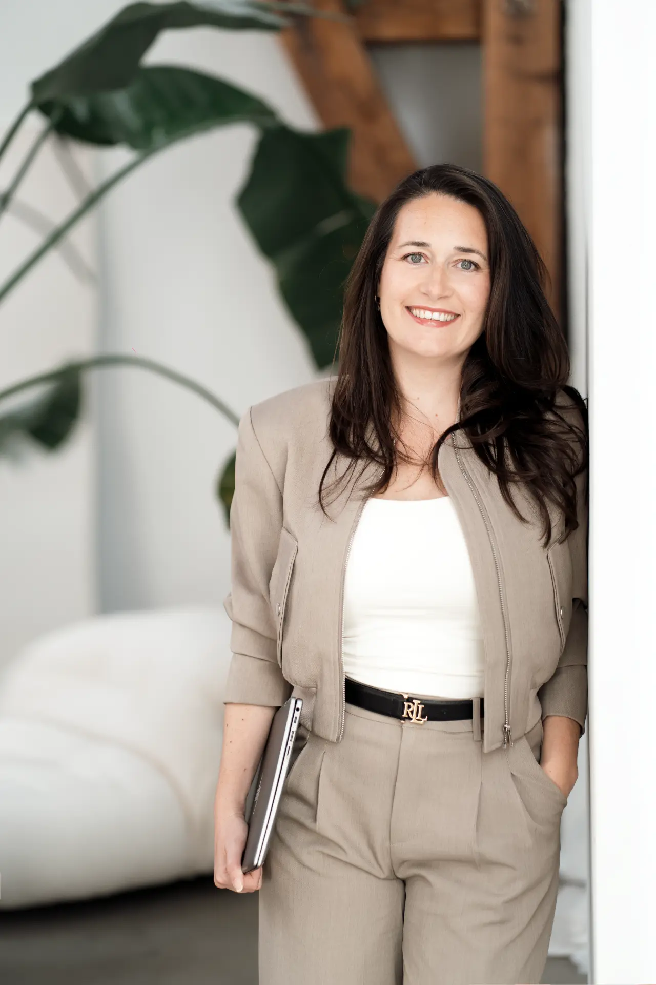 Suzana standing with her laptop in a light interior