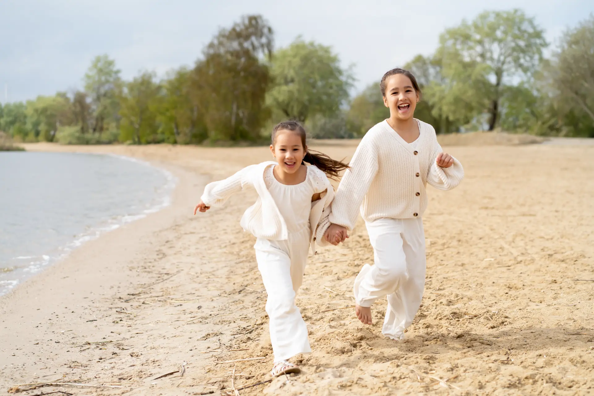 Two sisters running hand in hand along the shoreline