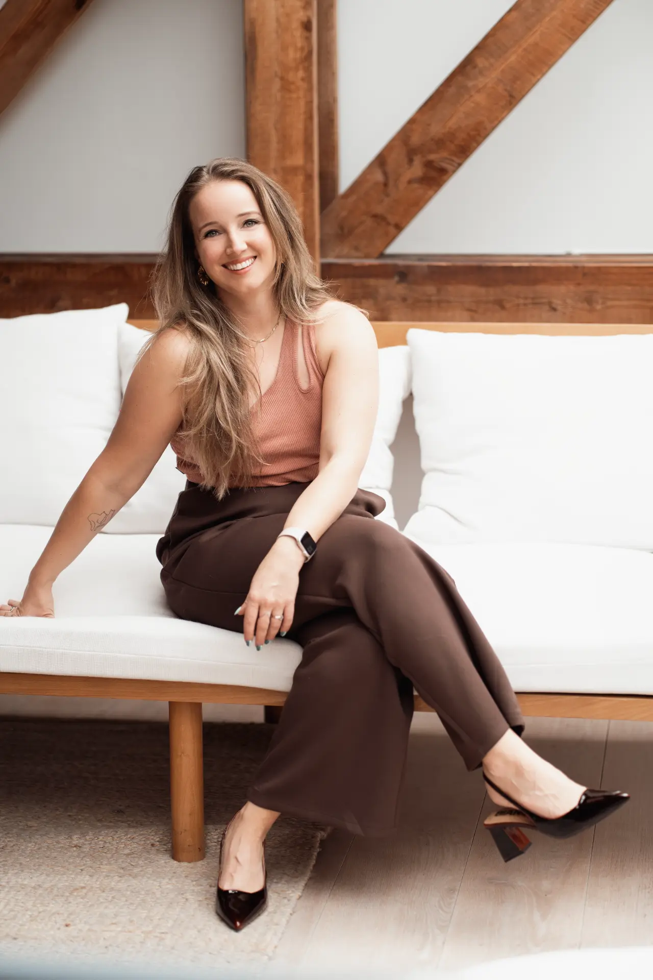Marina seated on a white sofa in rust and brown tones