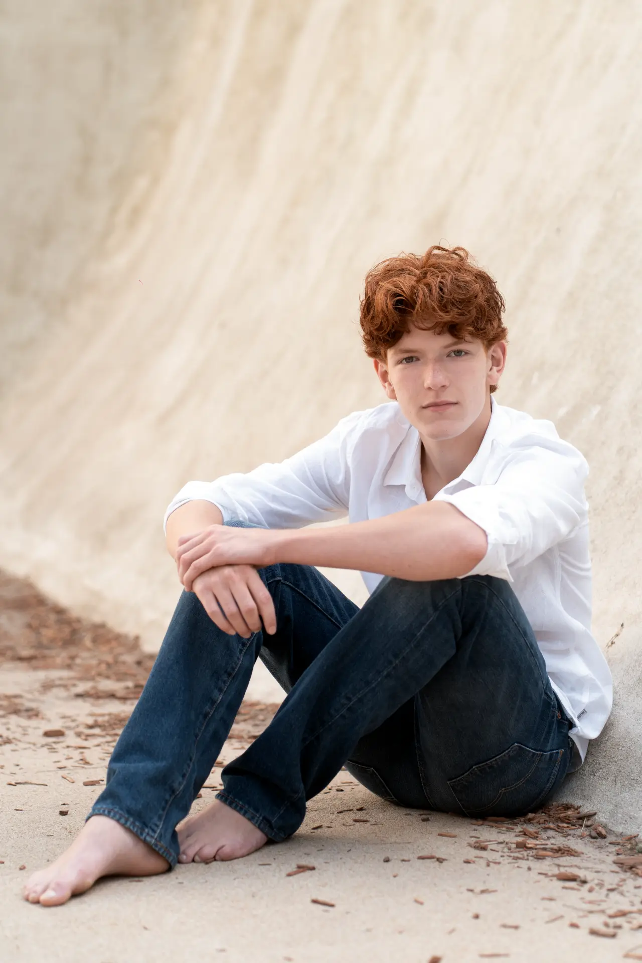 Shey seated against a softly curved pale wall