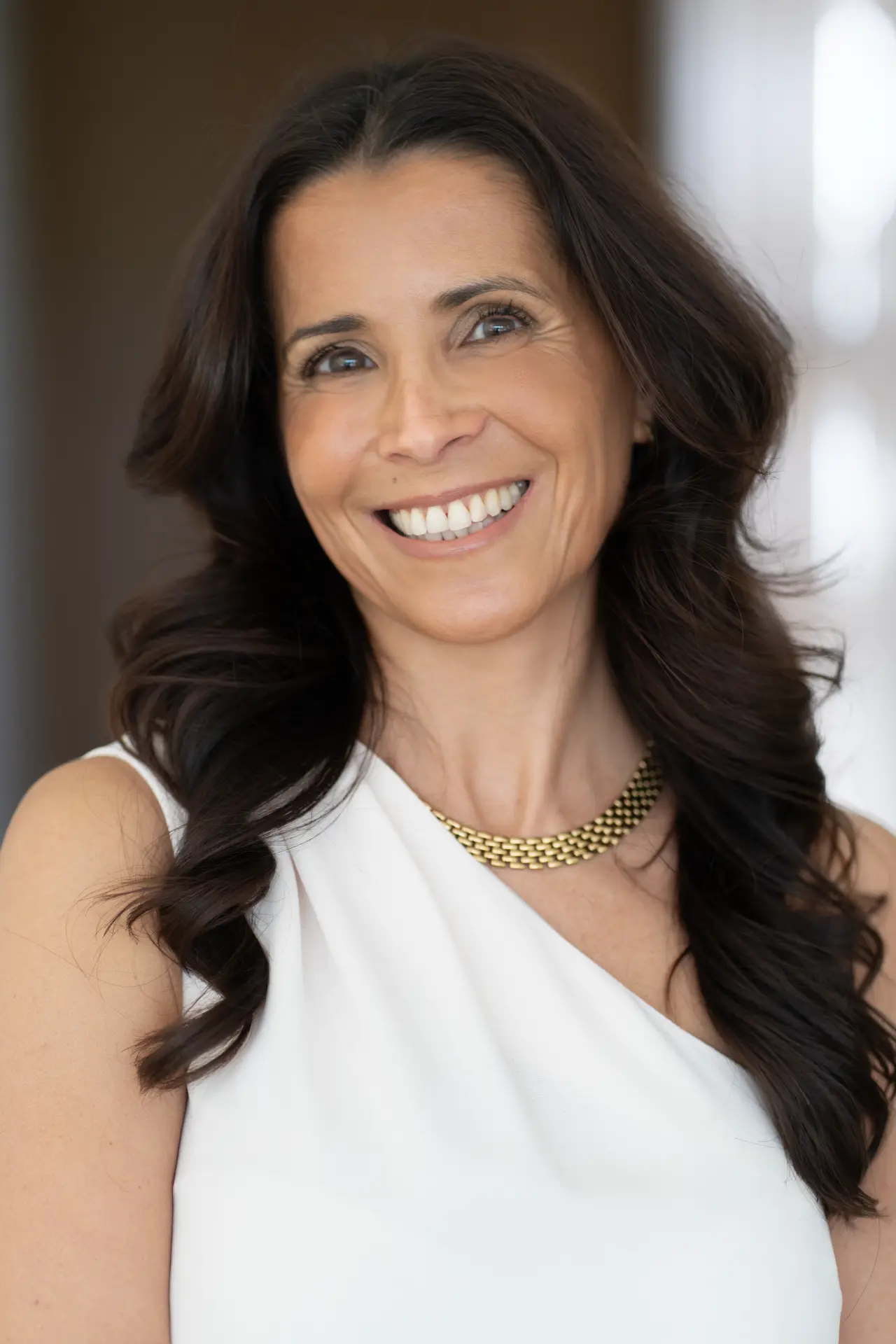Close branding portrait of a smiling woman in a white top with a gold necklace