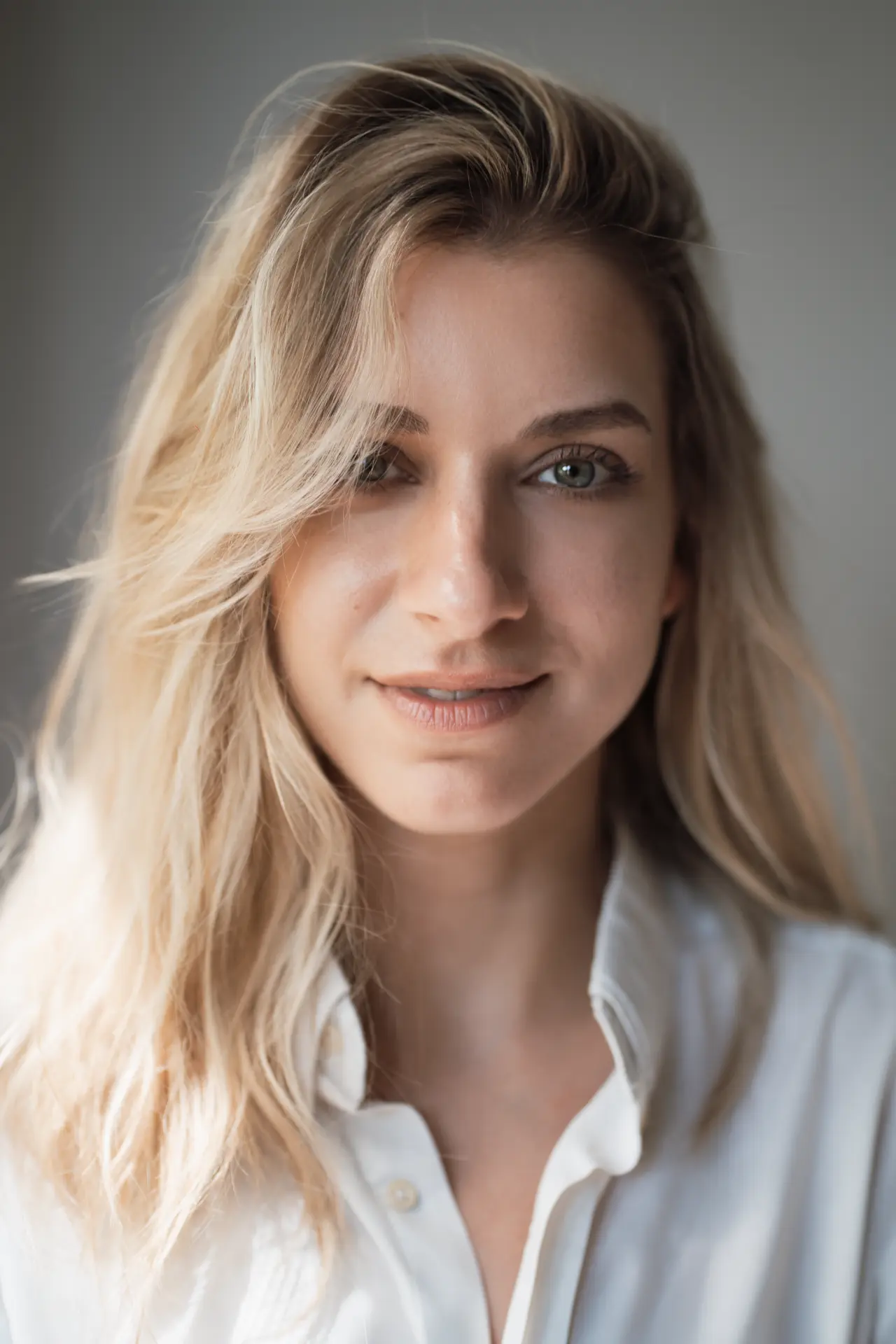 Lia in a white shirt against a soft grey wall