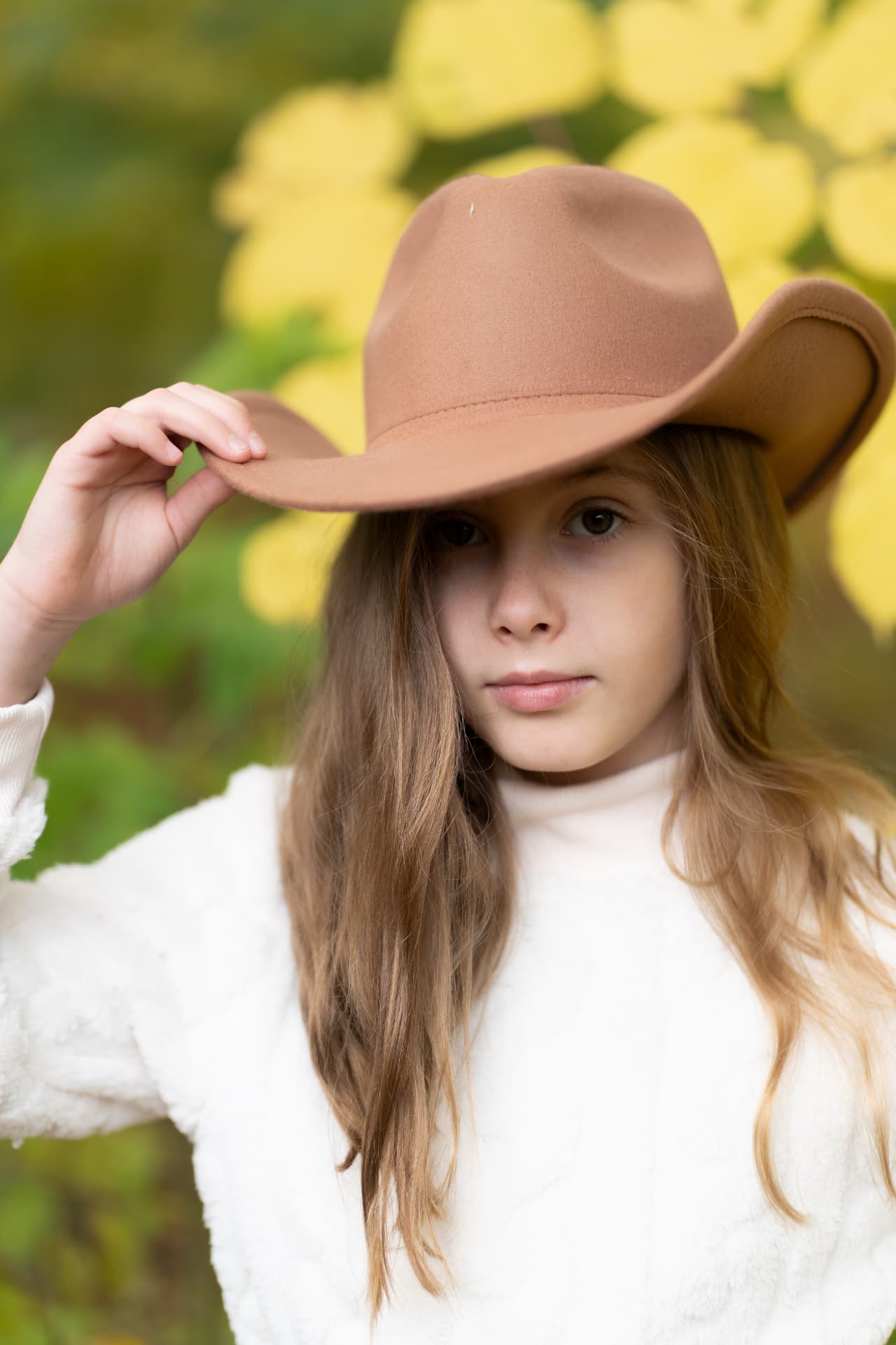 Girl in a warm brown hat among autumn leaves