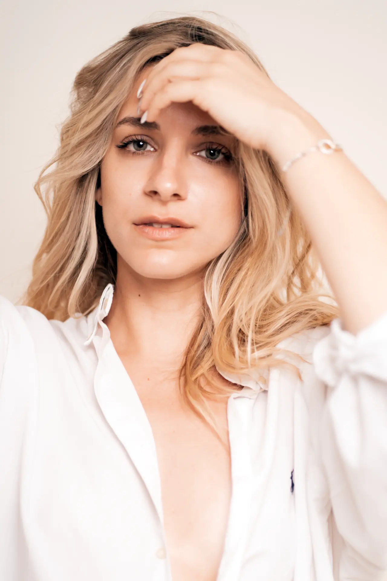 Lia in a white shirt with her hand resting above her brow