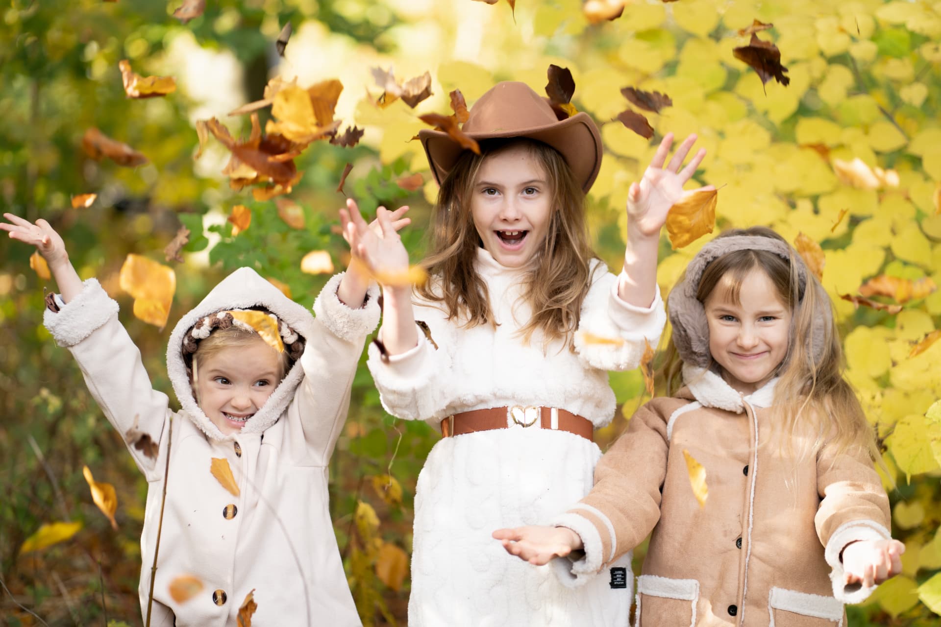 Three girls throwing autumn leaves in the air