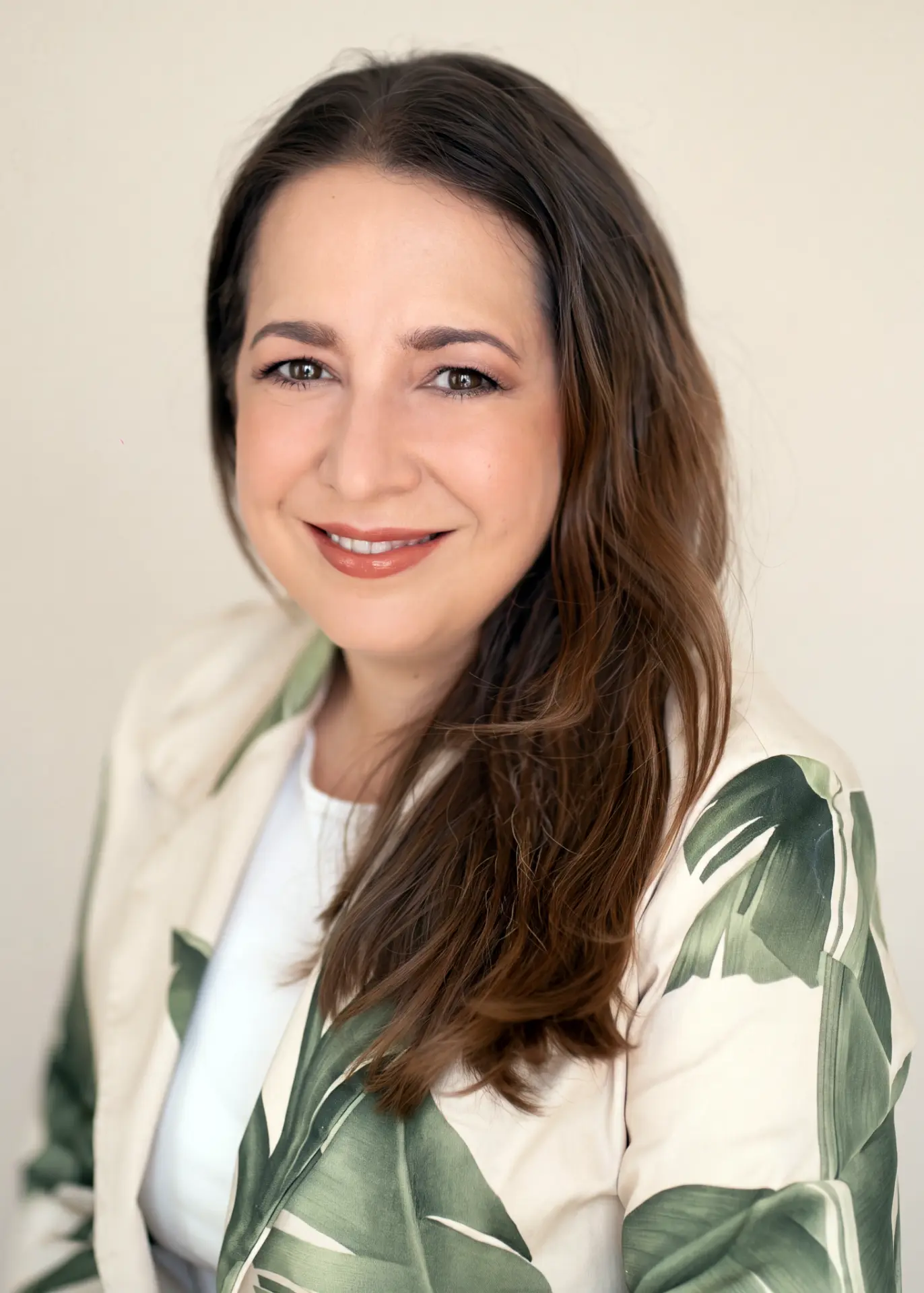 Woman in a botanical jacket against a warm ivory backdrop