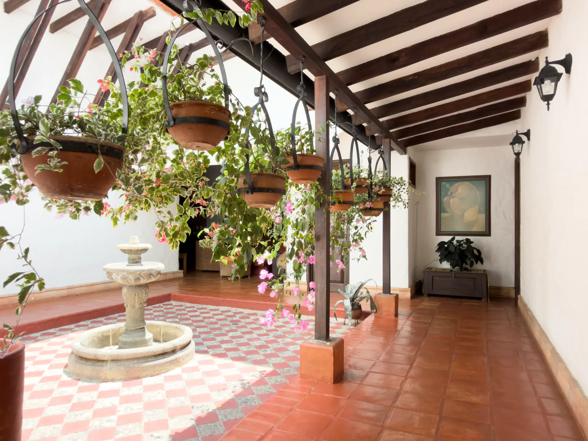 Covered corridor with terracotta pots hanging from dark wooden beams