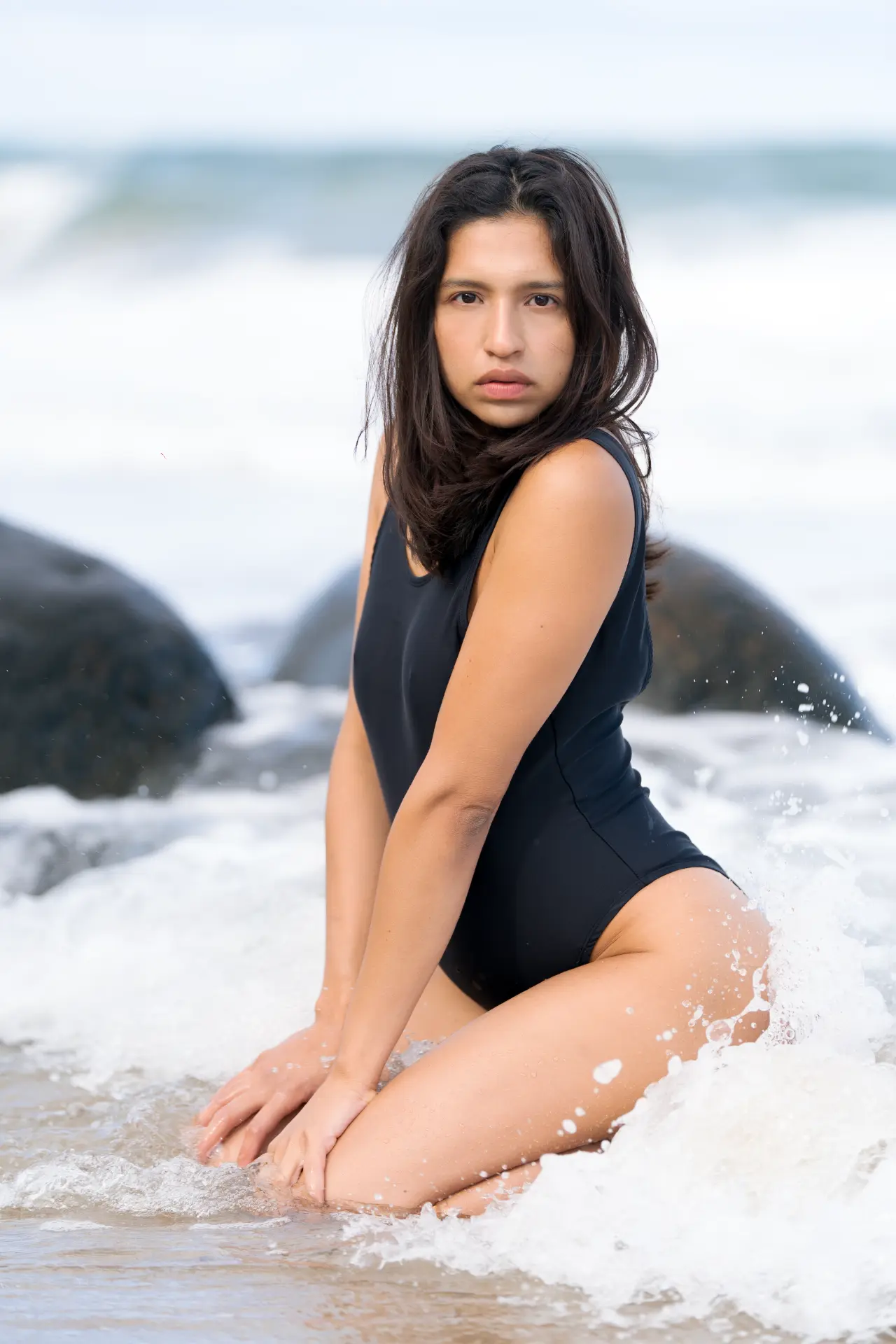 Ana kneeling in white breaking surf