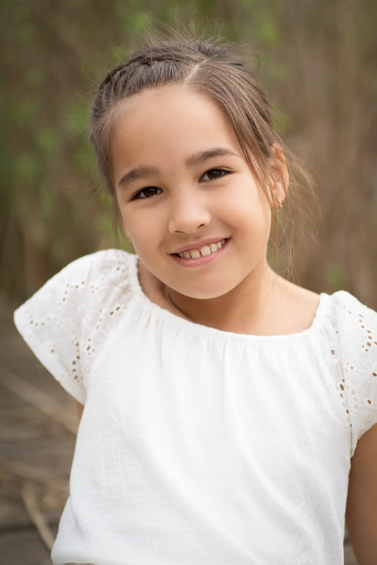 Portrait of a girl in a white eyelet top smiling in the reeds
