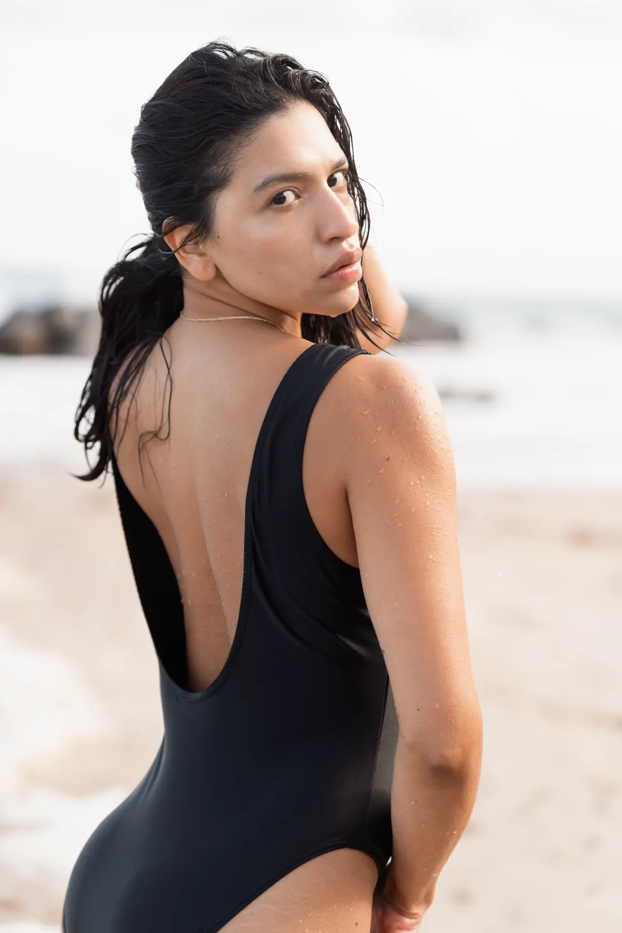 Ana in a black swimsuit glancing back over her shoulder
