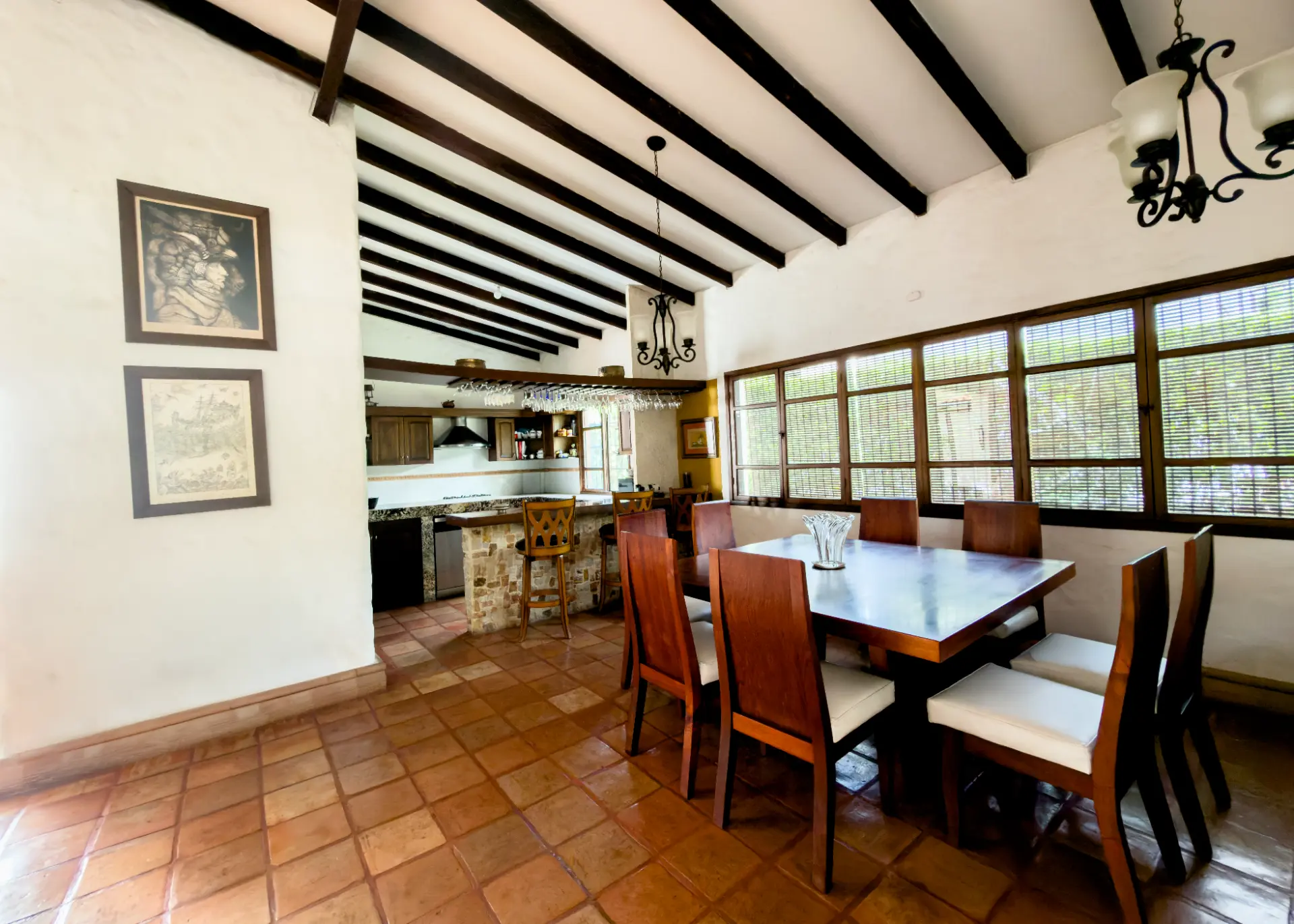Dining room with dark ceiling beams opening onto the kitchen and breakfast bar