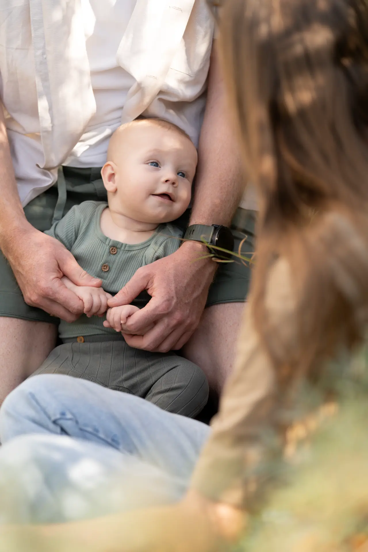 Baby smiling up from his father's lap