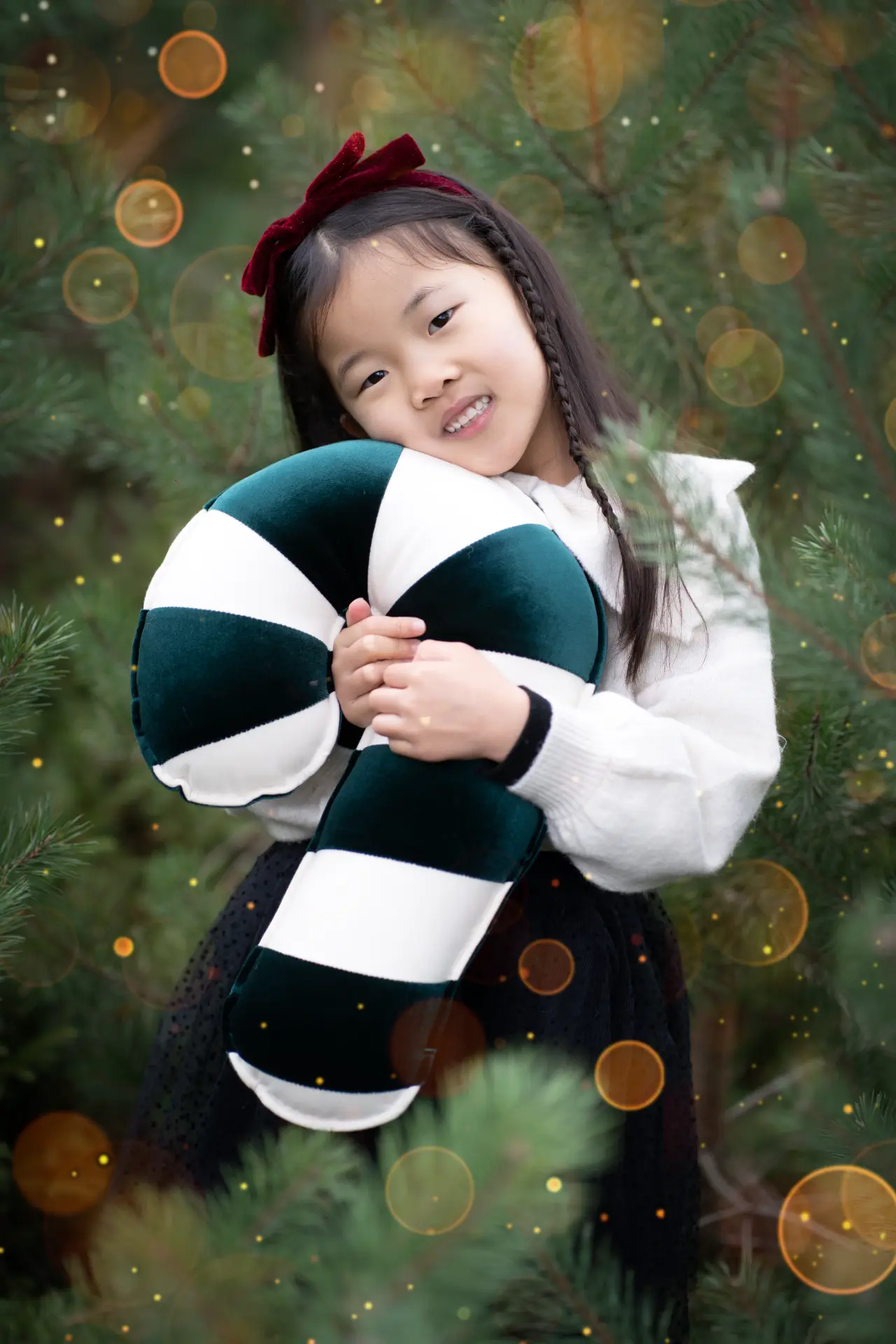 Girl hugging a striped cushion among glowing Christmas lights