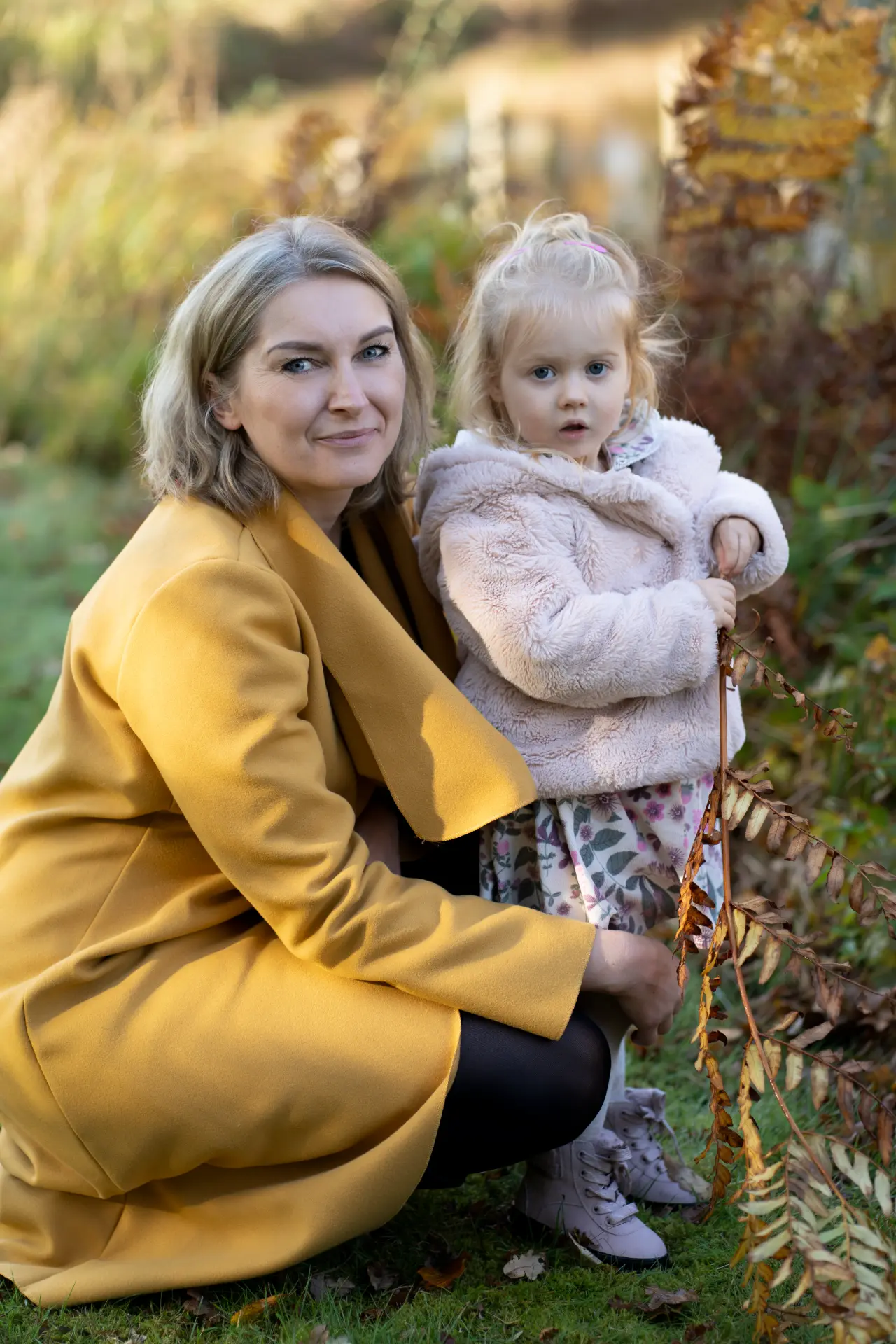 Mother and daughter seated together among golden ferns