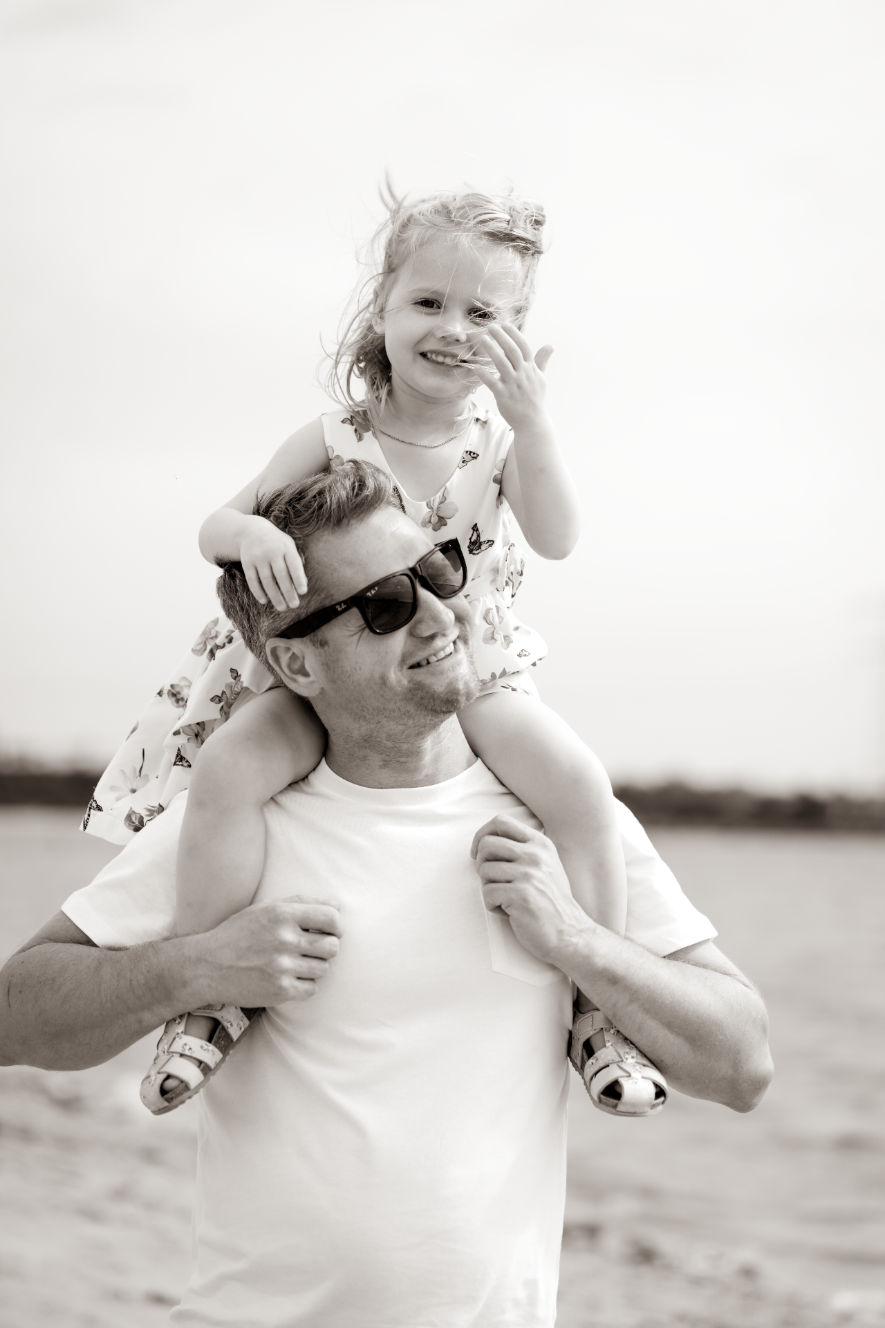 Father carrying his daughter on his shoulders by the water