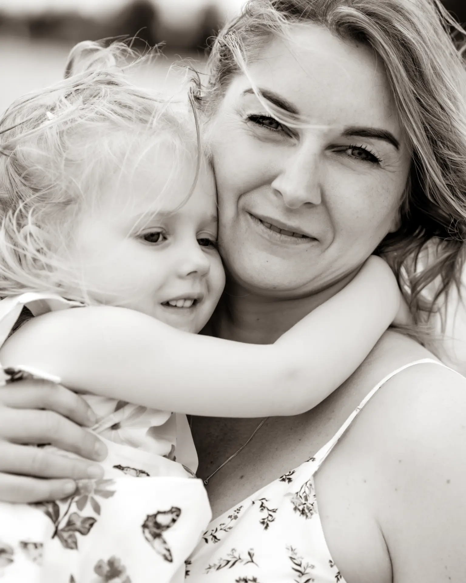 Mother and daughter cheek to cheek in a close black and white embrace