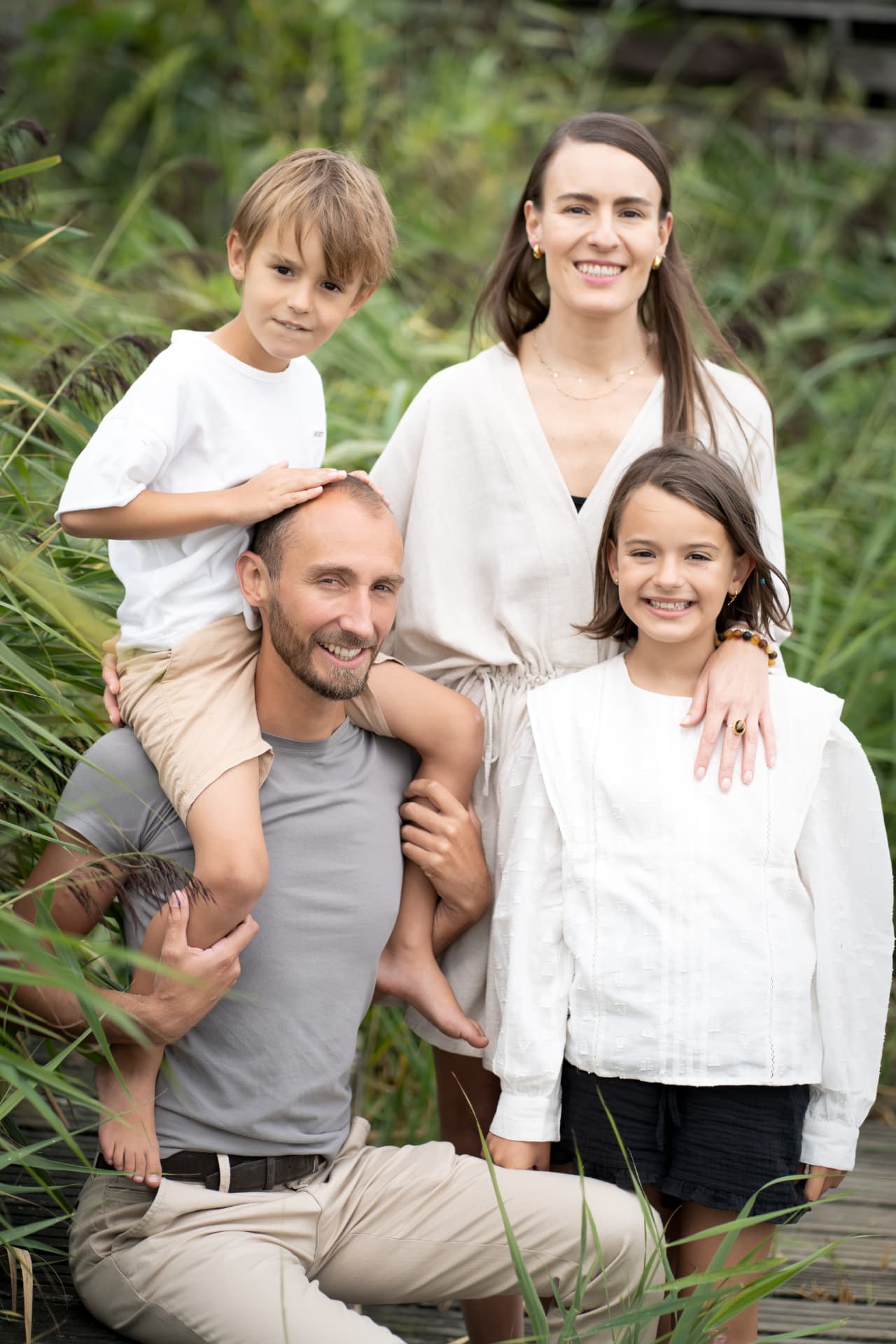 Family of four smiling together among tall green reeds