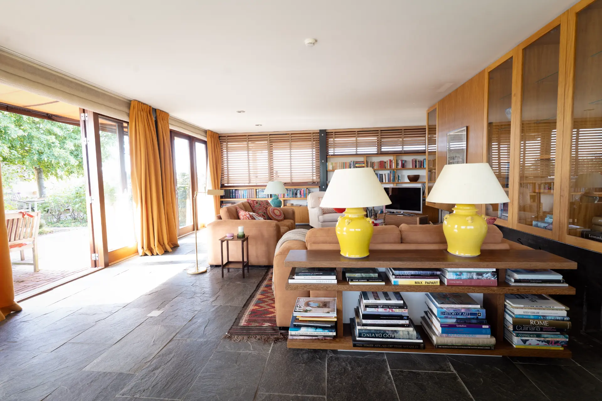 The sitting room opening onto the garden, with yellow ceramic lamps and shelves of books