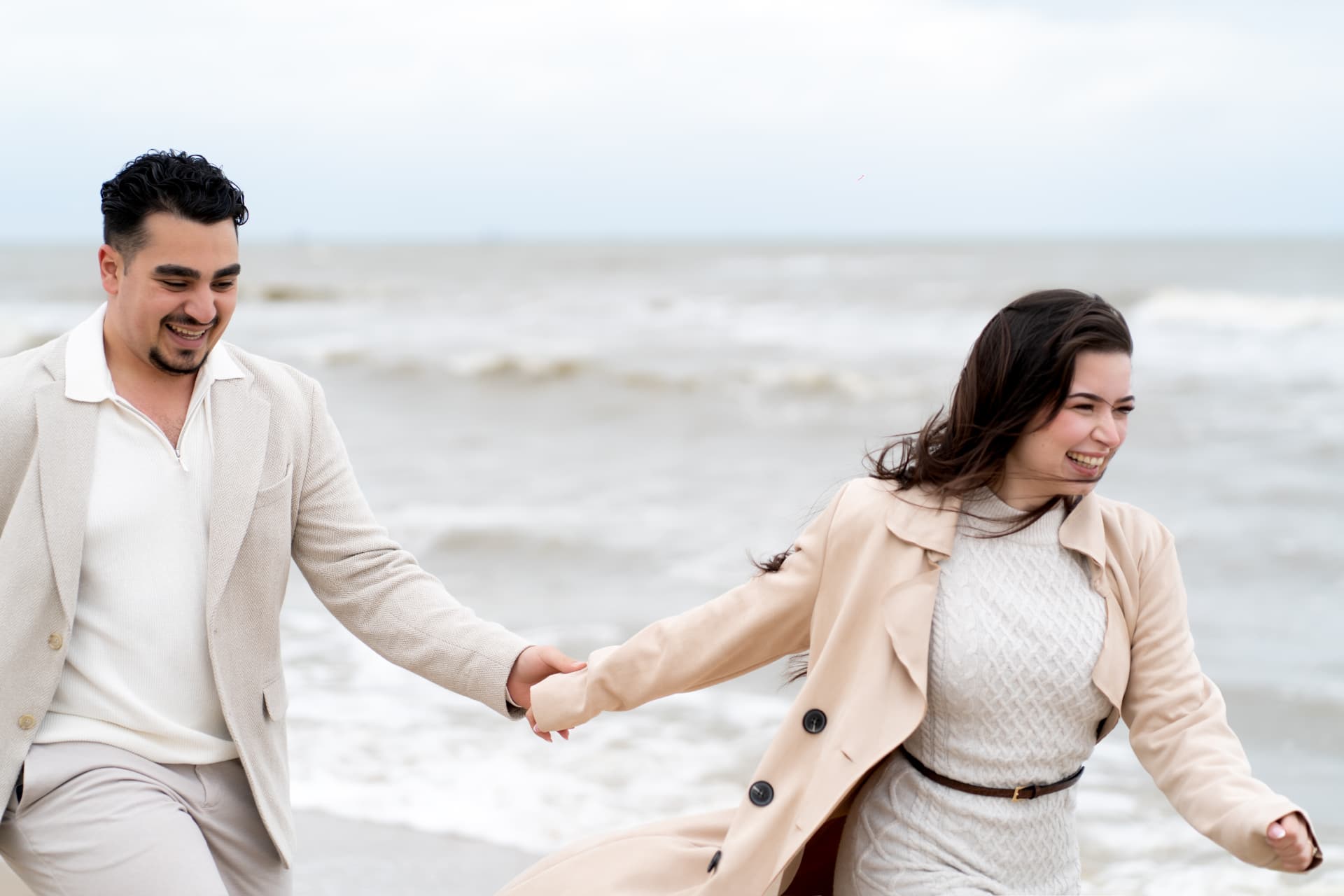 N and Y running hand in hand beside the sea