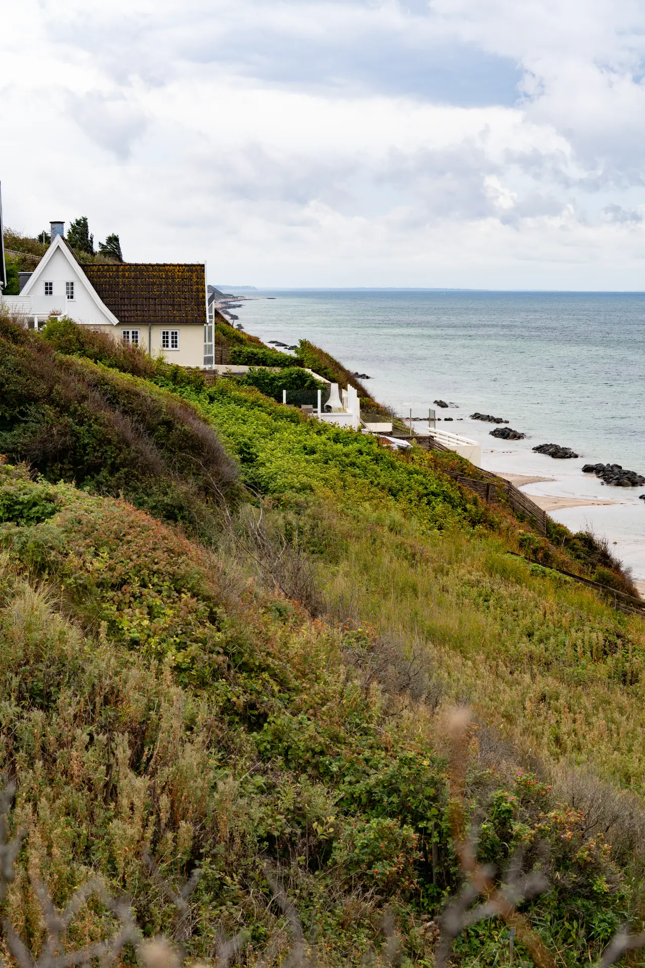 White house above a green cliff overlooking the Danish coast