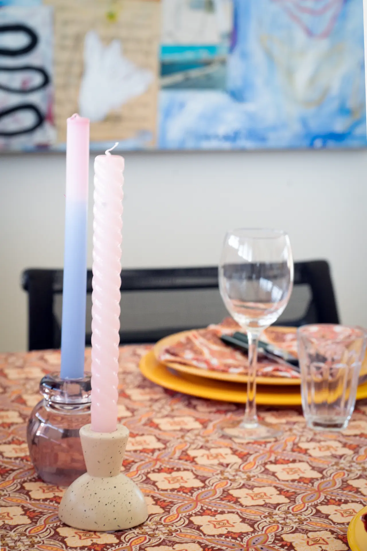 Pink twisted candles and a wine glass on the patterned tablecloth