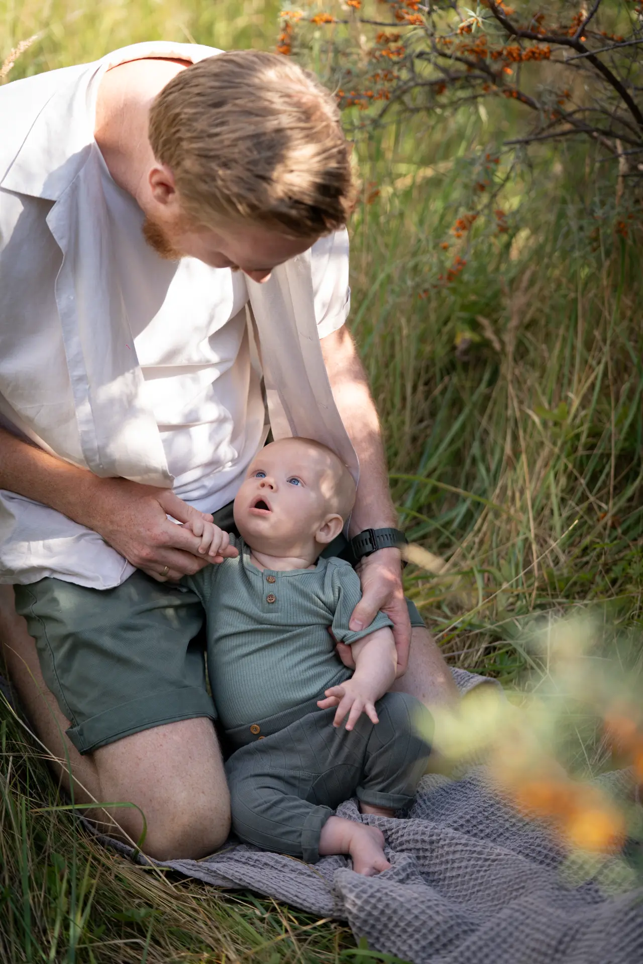 Father kneeling in tall grass with his baby