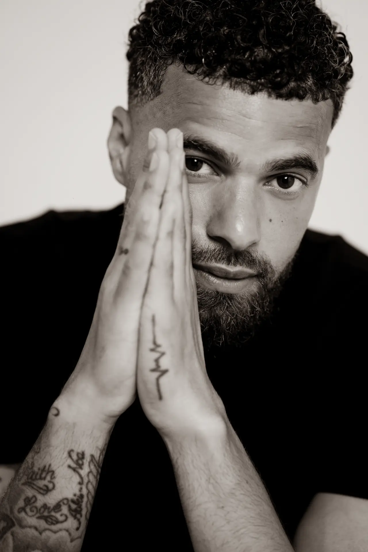 Black and white portrait of a man with his hands beside his face